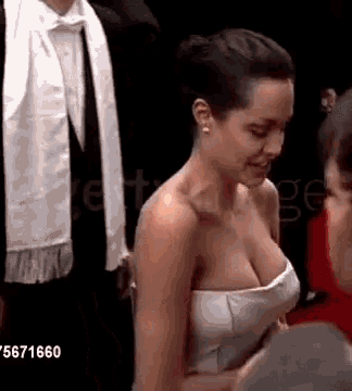 a woman in a white strapless dress is talking to a man in a tuxedo .