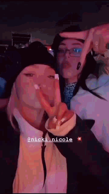 a couple of girls are standing next to each other and making a peace sign .