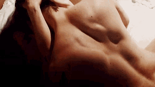 a man and a woman are laying on a bed without shirts .