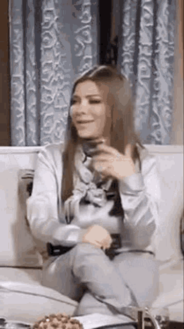 a woman is sitting on a couch holding a cup of coffee in her hand .