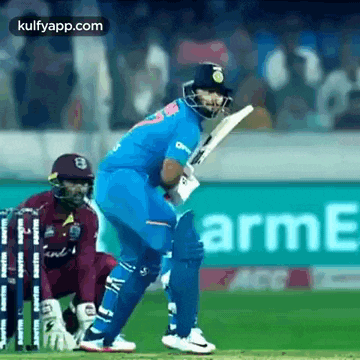a cricket player is swinging a bat at a cricket ball while another player watches .