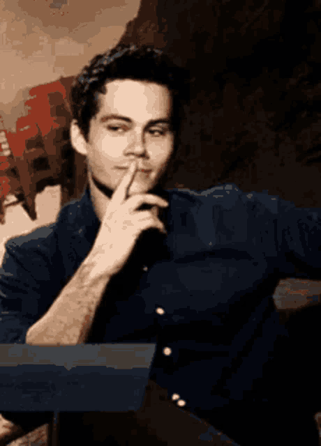 a man in a blue shirt holds his hand to his mouth