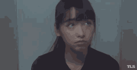 a woman with her eyes closed is sitting in a dark room .