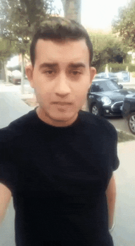 a man wearing a black shirt is standing in front of a parking lot