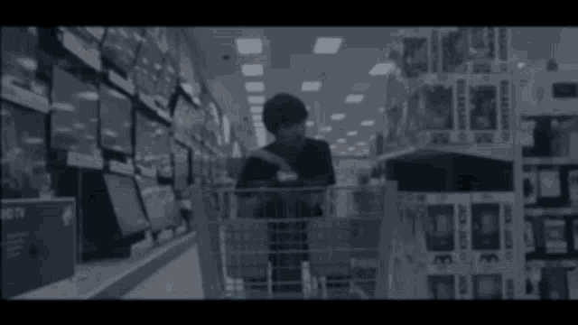 a man in a black t-shirt is standing in a store with a blurred background .
