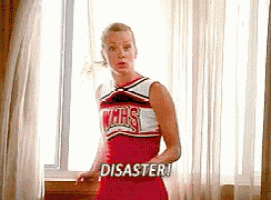 a cheerleader is standing in front of a window and says disaster .