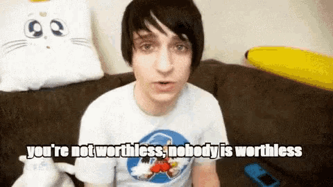 a young man is sitting on a couch and saying you 're not worthless nobody is worthless .