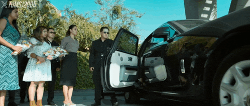 a group of people standing in front of a car with x films 2005 written on the bottom right