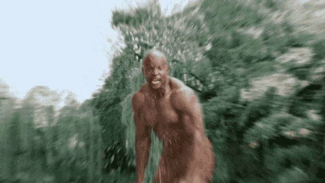 a naked man is running through the woods .