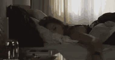 a woman is laying in bed with her legs crossed and a lamp in the background .