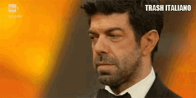 a man in a tuxedo and bow tie is crying with the words trash italiano written on the bottom .