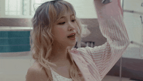 a woman in a pink and white striped shirt is singing into a microphone