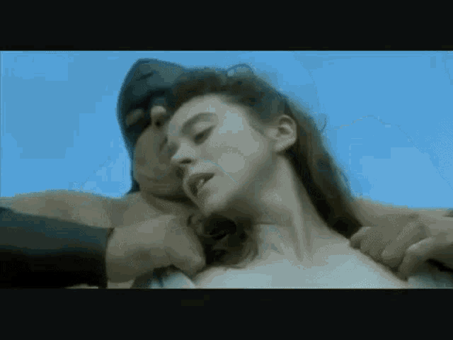 a man in a mask is holding a woman 's neck in a video .
