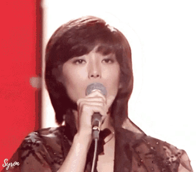 a woman singing into a microphone with syron written on the bottom left