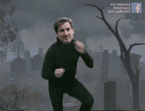 a man in a black suit is dancing in front of a cemetery
