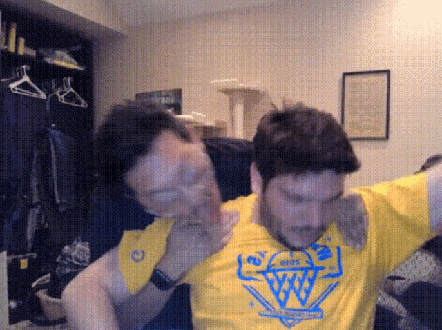 a man wearing a yellow shirt with a blue logo on it