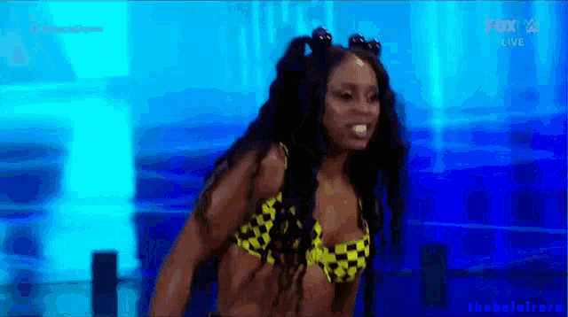 a woman in a bikini is standing in front of a blue background .