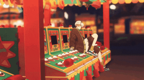 a man sits in front of a carnival game with a red hat