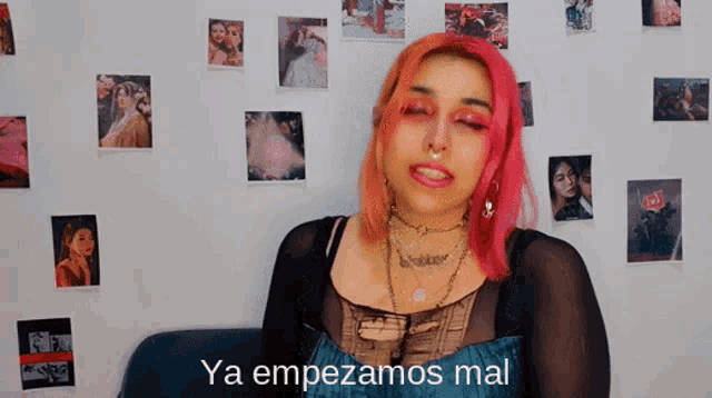 a woman with pink hair says ya empezamos mal in front of pictures on the wall