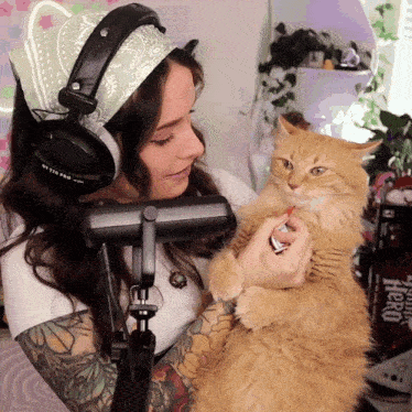 a woman wearing headphones is holding a cat