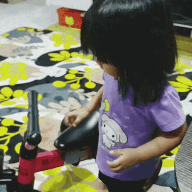 a little girl wearing a purple shirt that says hello kitty