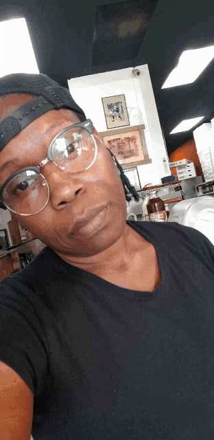 a woman wearing glasses and a black shirt looks at the camera