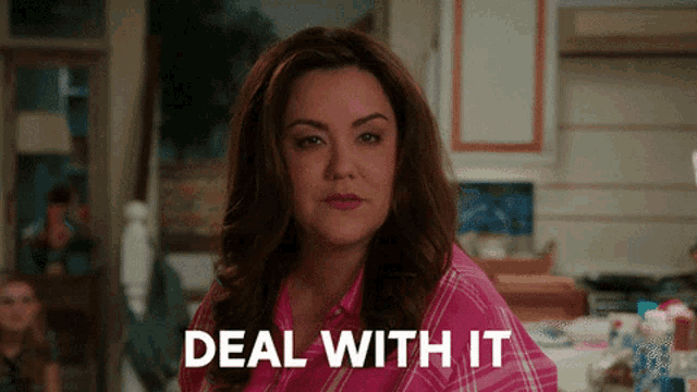 a woman in a pink shirt says " deal with it " in front of her
