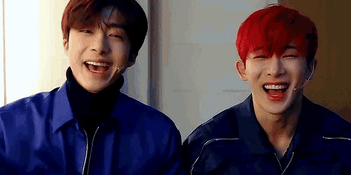 two young men with red hair are laughing together while wearing blue jackets .
