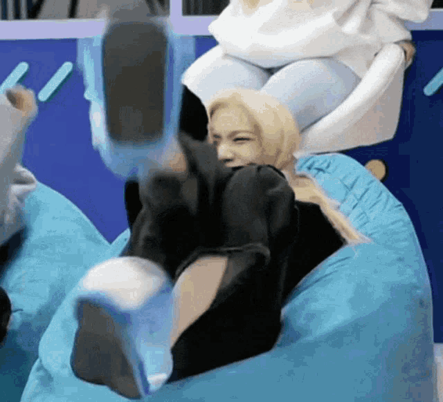 a woman laying on a blue bean bag chair with her feet up