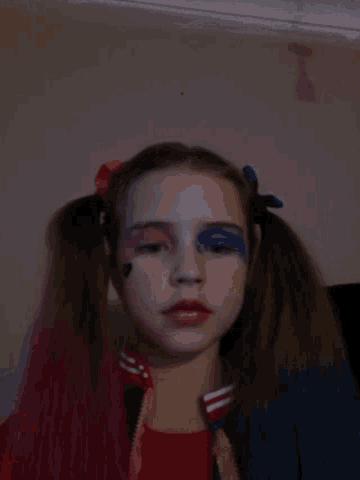 a girl with red hair and blue eye makeup looks down