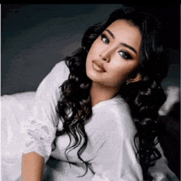 the woman is wearing a white robe and looking at the camera .
