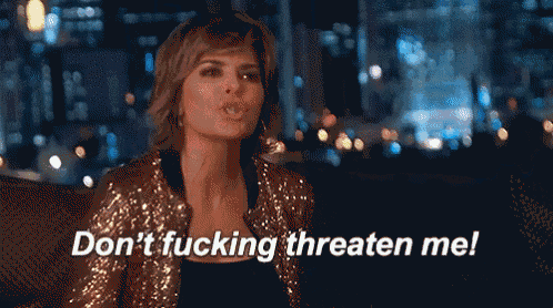 a woman sitting on a couch with the words " do n't fucking threaten me " written below her