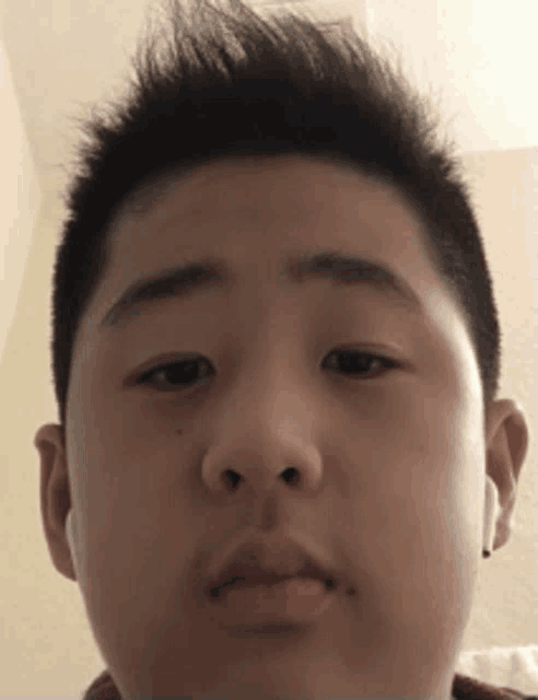 a young boy wearing ear buds looks at the camera with a serious look on his face