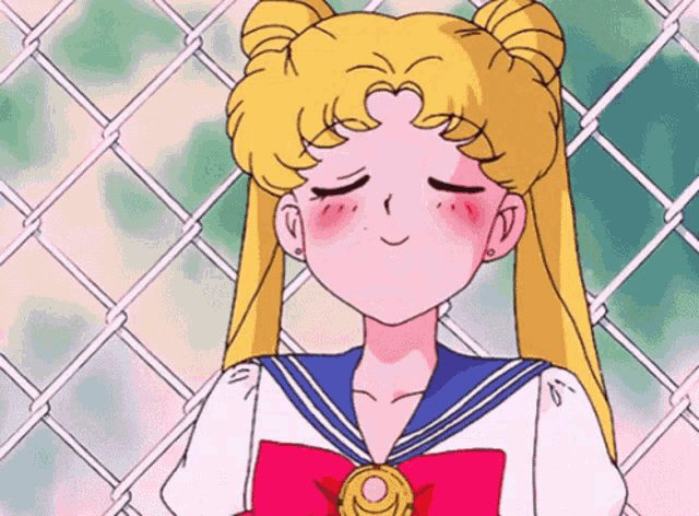 a girl in a sailor suit with her eyes closed stands in front of a chain link fence