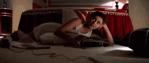 a woman is laying on a bed with a magazine on the floor .