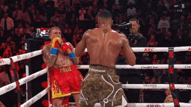 two boxers are fighting in a boxing ring while a cameraman takes a picture .