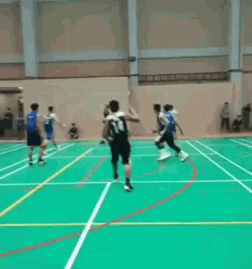 a group of basketball players are playing a game on a green court