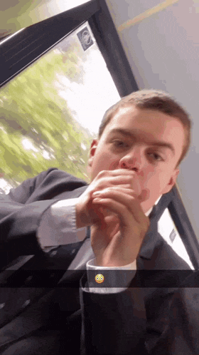 a man in a suit is sitting on a bus with a smiley face on his shirt