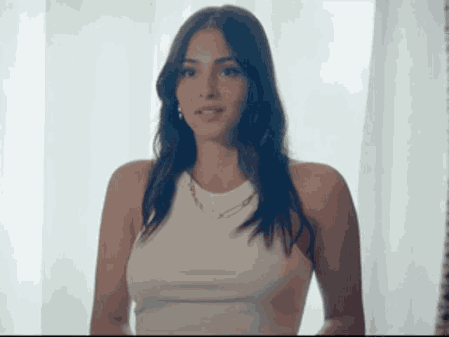 a woman is wearing a white tank top and a necklace .
