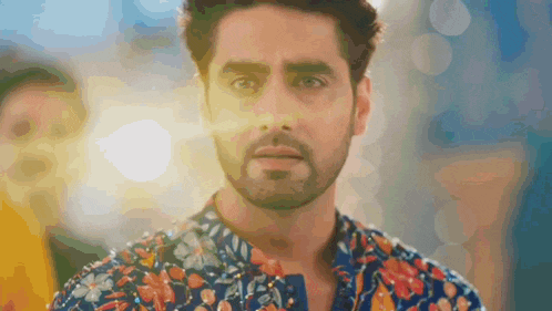 a man with a beard is wearing a colorful shirt and looking at the camera .