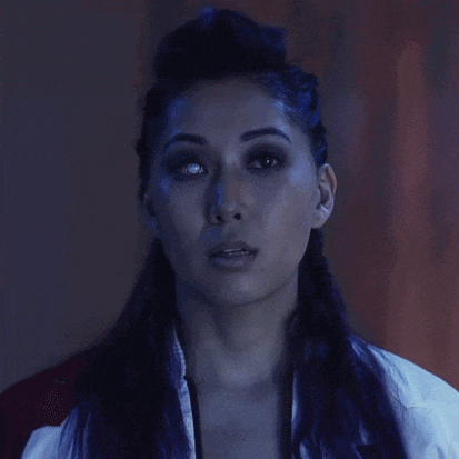 a close up of a woman 's face with purple hair and a white shirt that says ' karate ' on it