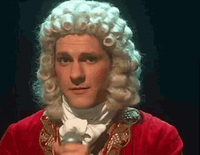 a man in a wig is holding a microphone in his hand .