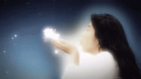 a woman blowing a white glowing object in the air