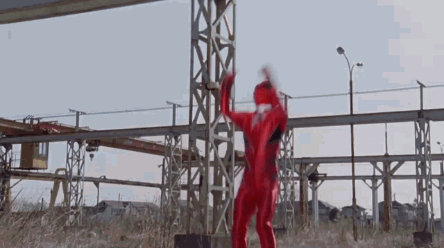 a man in a red and black superhero costume is running in a field