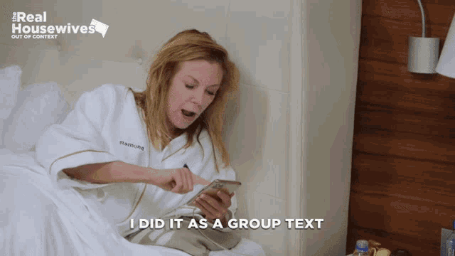 a woman sitting on a bed looking at her phone with a real housewives logo behind her