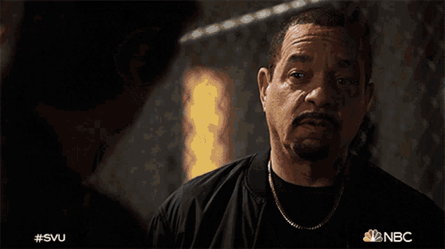 a man in a black jacket and gold chain talks to another man in a nbc advertisement