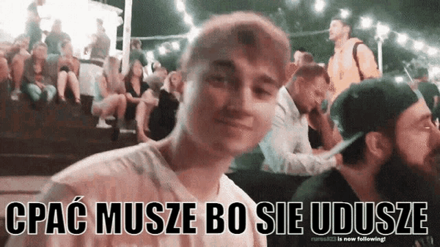 a man stands in front of a crowd with the words " cpac muse bo sie udusze " written below him