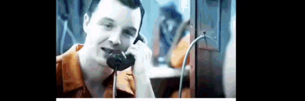 a man is talking on a pay phone and smiling
