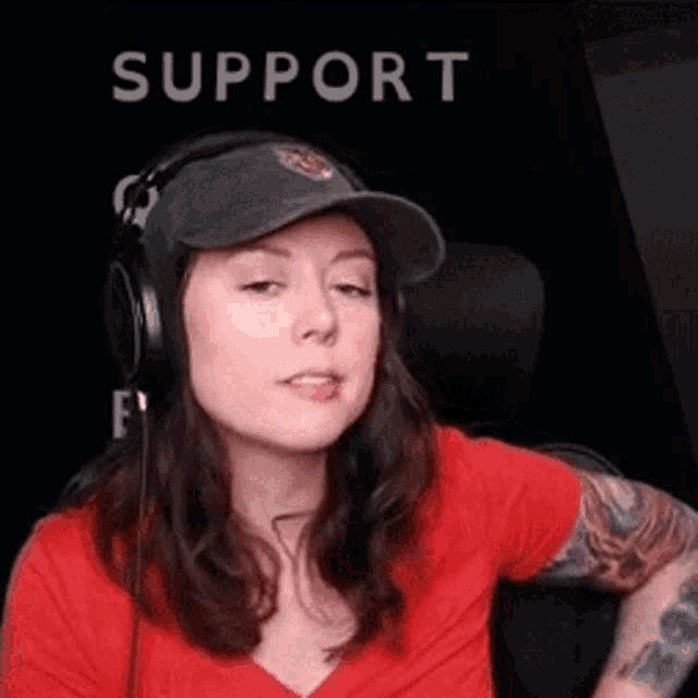 a woman wearing headphones and a baseball cap is sitting in a chair .