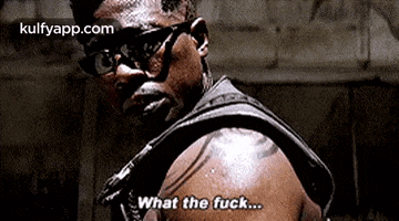 a man with glasses and a tattoo on his arm is talking to someone .